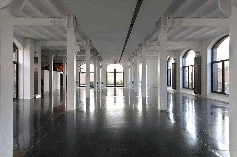 Großes, helles Office mit weißen Wänden, hohen Decken und großen Fenstern, ideal für moderne Arbeitsplätze oder kreative Bürogestaltung.