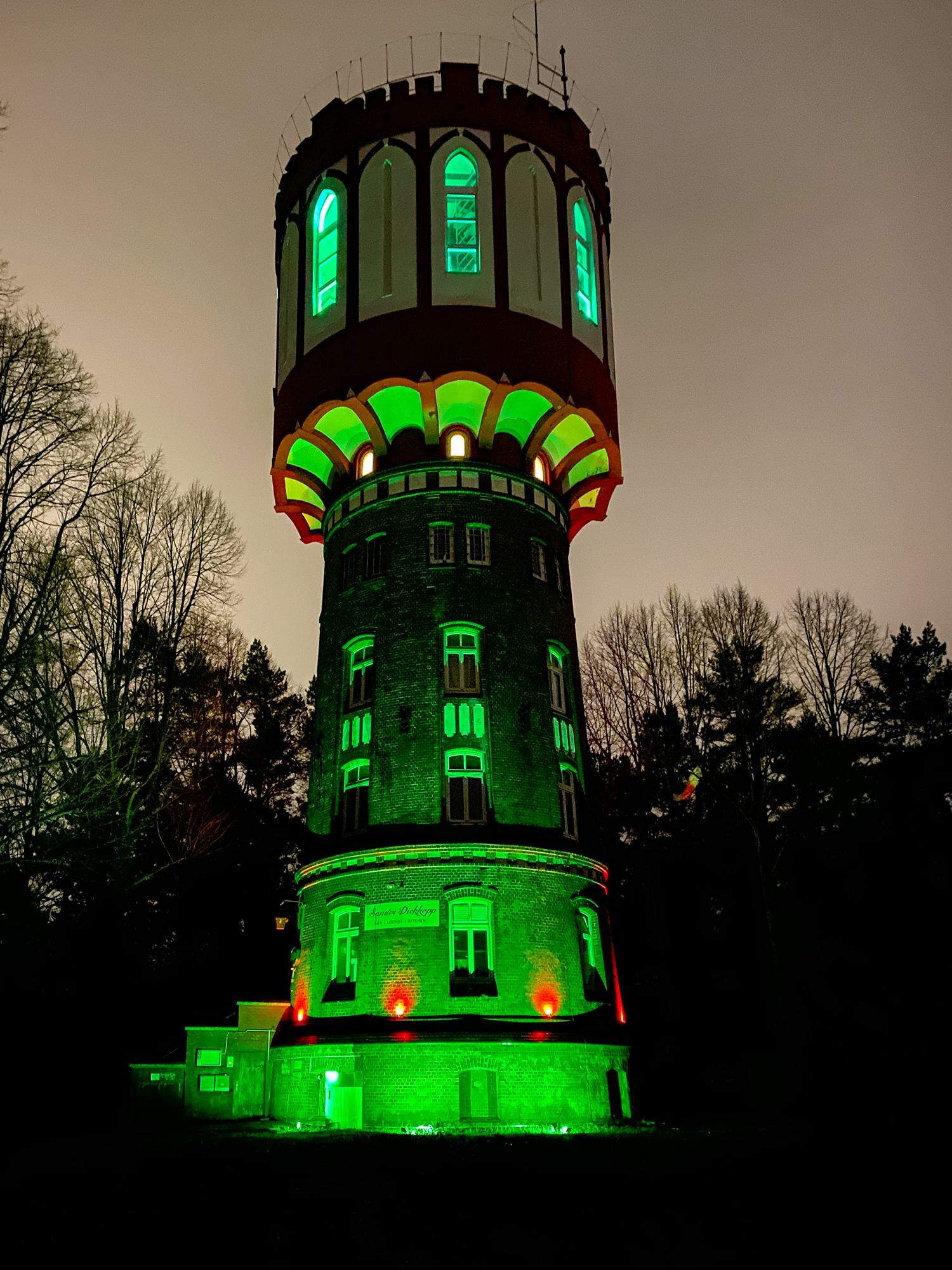 Leuchtturm bei Nacht mit grüner Beleuchtung, umgeben von Bäumen, stilvolles Motiv, das Innovation und Technik betont, ideal für SEO im Zusammenhang mit Architektur, Sehenswürdigkeiten und technischen Innovationen.