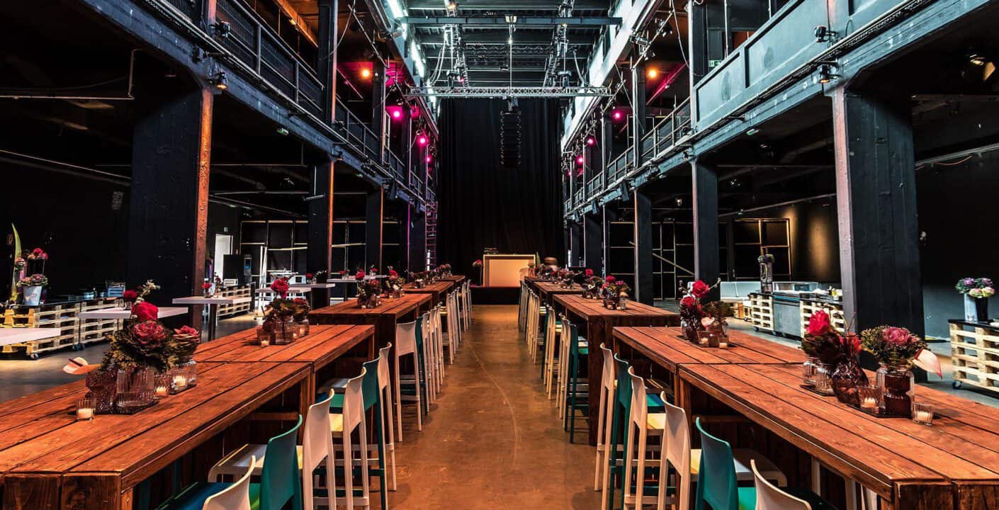 Moderne Industrielounge mit langer Holzbufetttafel für Events und Veranstaltungen in einem stilvollen Veranstaltungssaal.