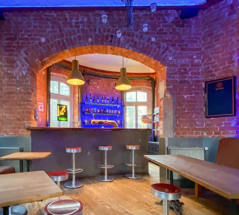 Gemütliche Bar mit rotem Backstein, stylischer Beleuchtung und modernen Sitzgelegenheiten, ideal für Drinks und Geselligkeit.