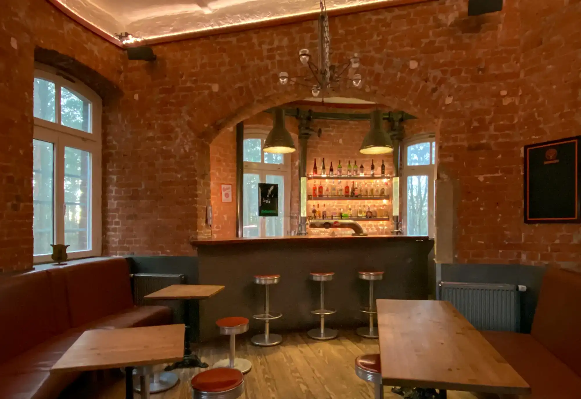 Gemütliche Bar mit Backsteinwänden, rustikalem Flair, komfortablen Sitzgelegenheiten und stilvoller Beleuchtung, perfekt für entspannte Abende in einer rustikalen Atmosphäre.