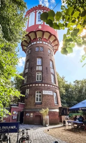 sander dickopp 07 Hoch hinaus: Der ikonische Wasserturm in Hannover, umgeben von Natur, dient heute als Gastronomiestandort mit gemütlichen Sitzmöglichkeiten unter Sonnenschirmen, ideal für entspannte Treffen und kulinarische Genussmomente.